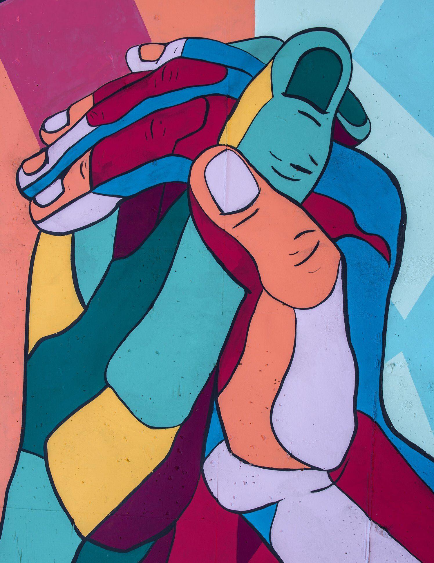 A vibrant mural features intertwined hands in bold colors like teal, orange, and red. The abstract, geometric style conveys unity and connection.