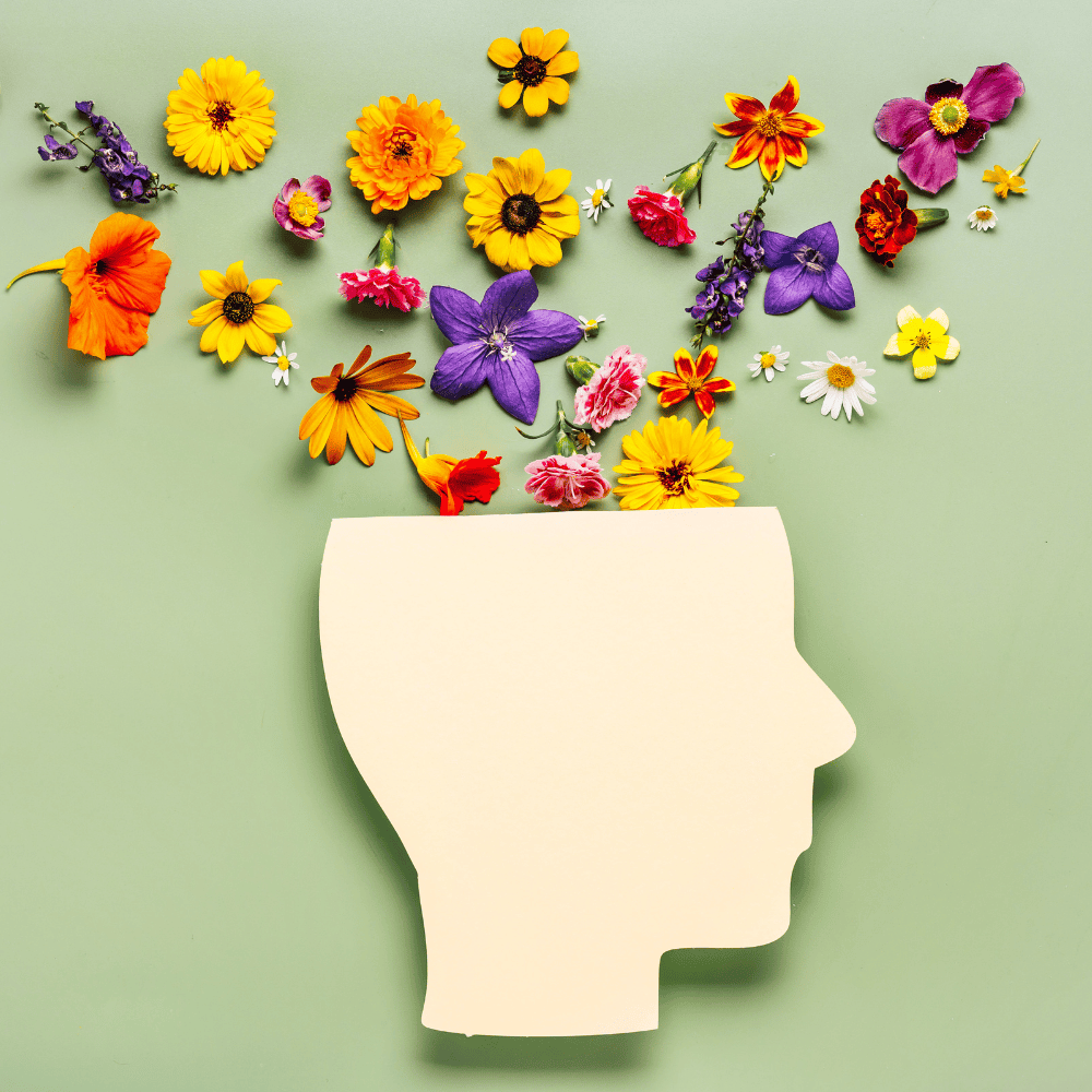 Illustration of a human head silhouette with colorful flowers representing mental health and behavior change support for wellness coaching.